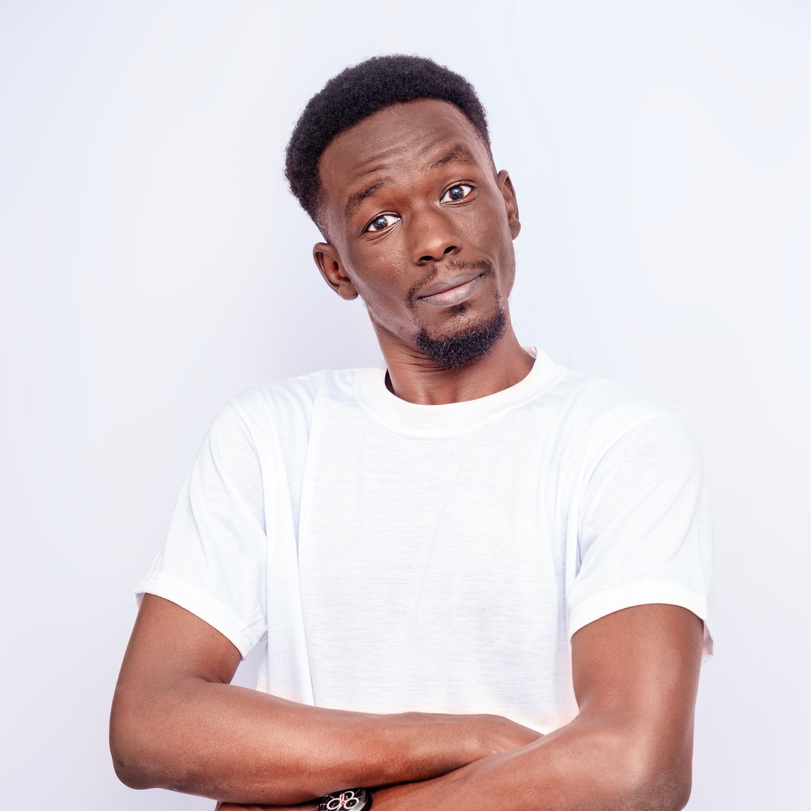 A confident man in a white shirt poses casually against a light background.